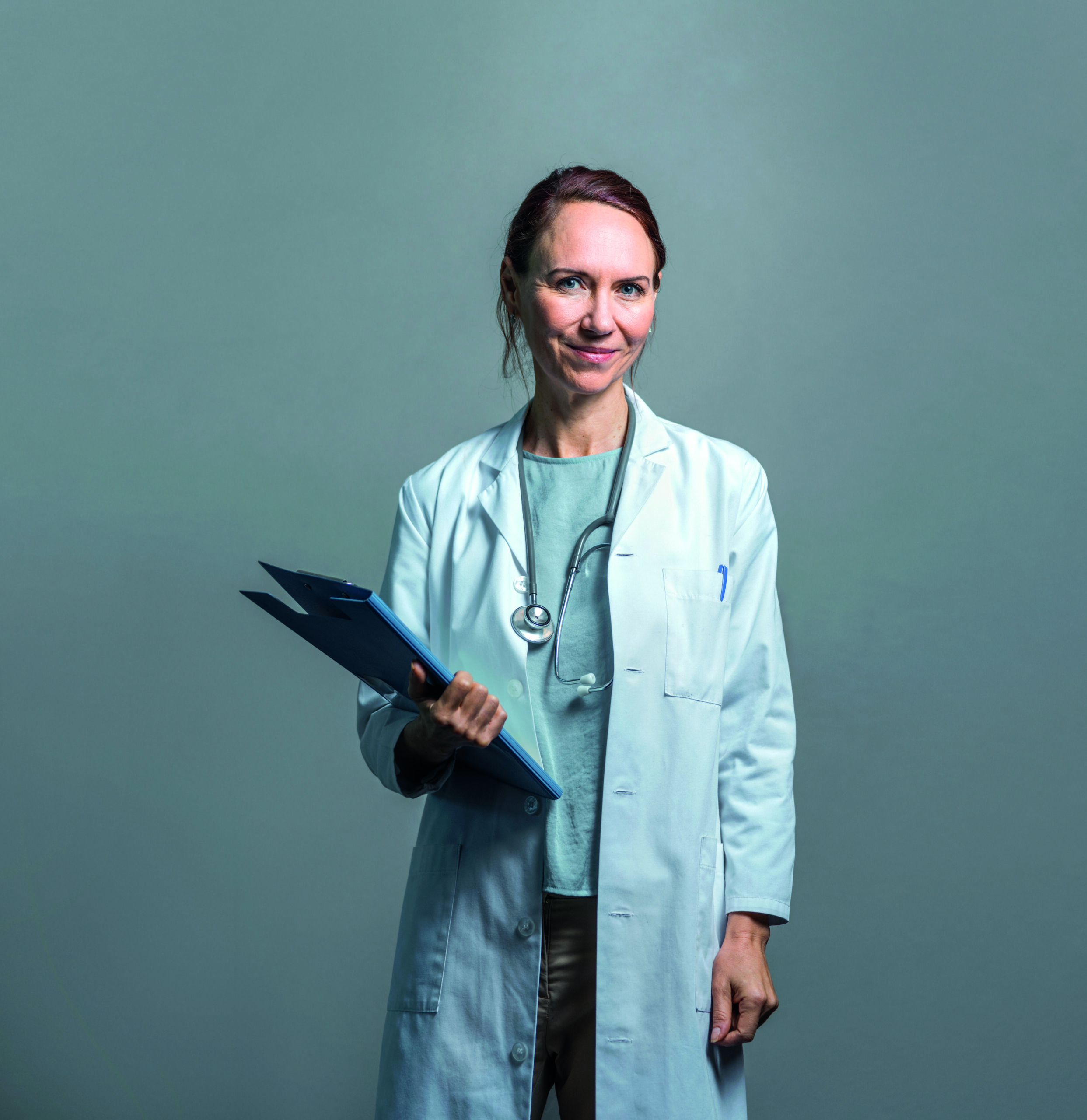 Portrait of confident mature doctor against wall